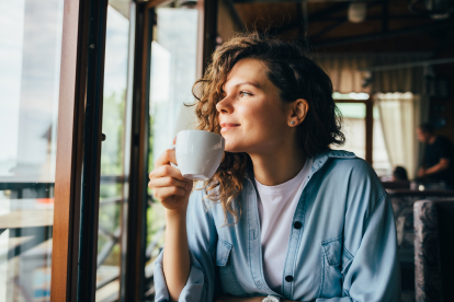 Mujer pensando en la vida mientras toma un café