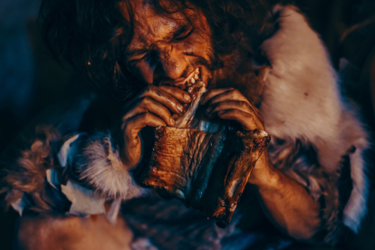 Recreación de un hombre comiendo en época prehistórica