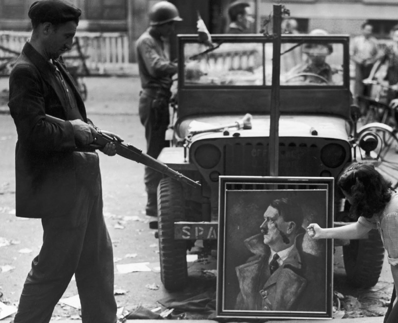 企業網站 La liberación trajo euforia y ansias de vengar la ocupación (en la imagen, dos parisinos “amenazan” a un retrato de Hitler)